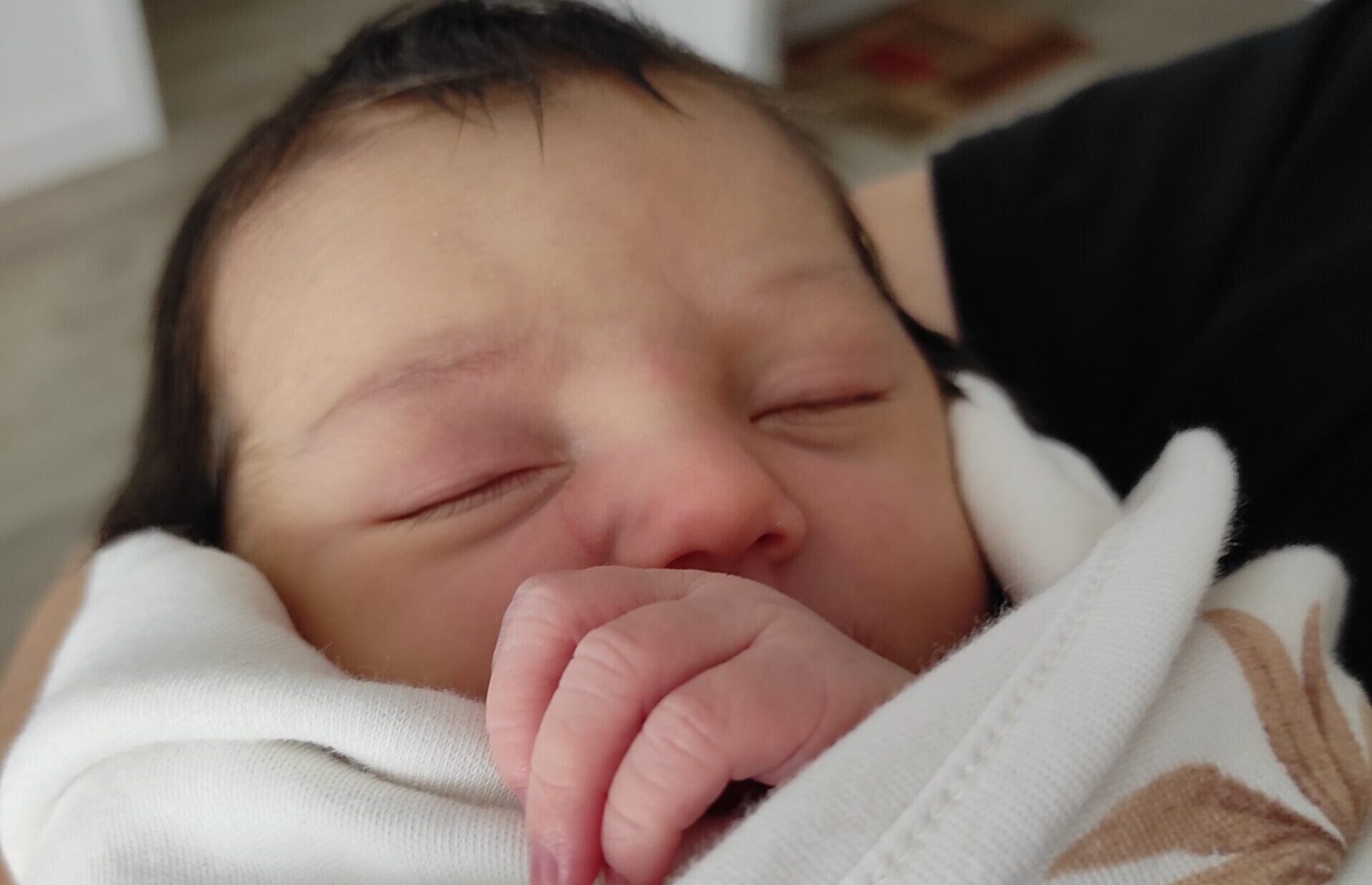 Neonato che dorme sul petto del genitore, simbolo di contatto, contenimento e sonno sicuro nel quarto trimestre.